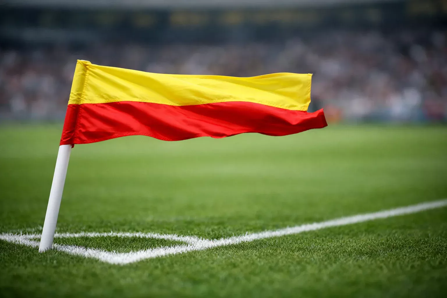Corner flag blowing strongly in the wind at a football stadium, showing windy match conditions