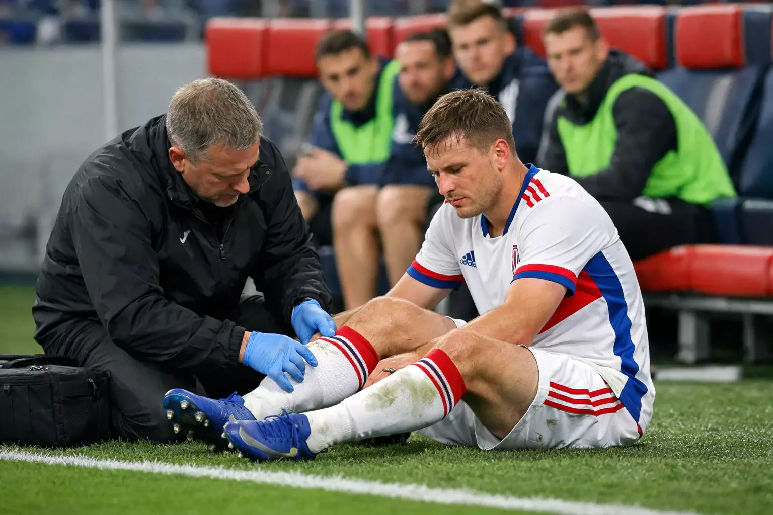 Football player receiving treatment from medical staff on the sideline during a match
