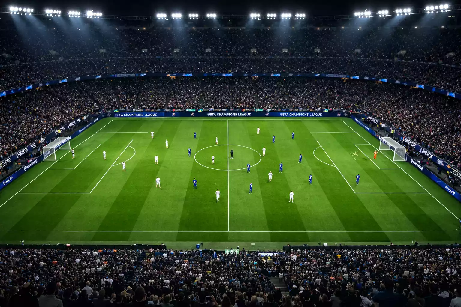 Wide shot of a Champions League match in progress at night, showing the full pitch and stadium atmosphere