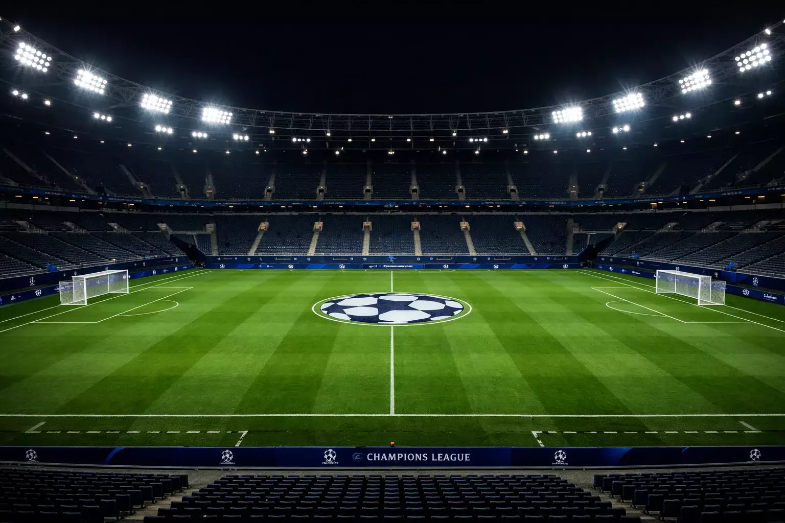 Football stadium at night with floodlights illuminating the pitch, ready for a Champions League match